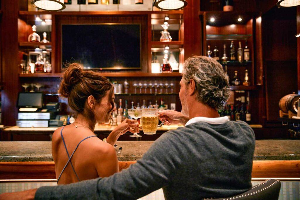 a man and woman clinking drinks at the bar