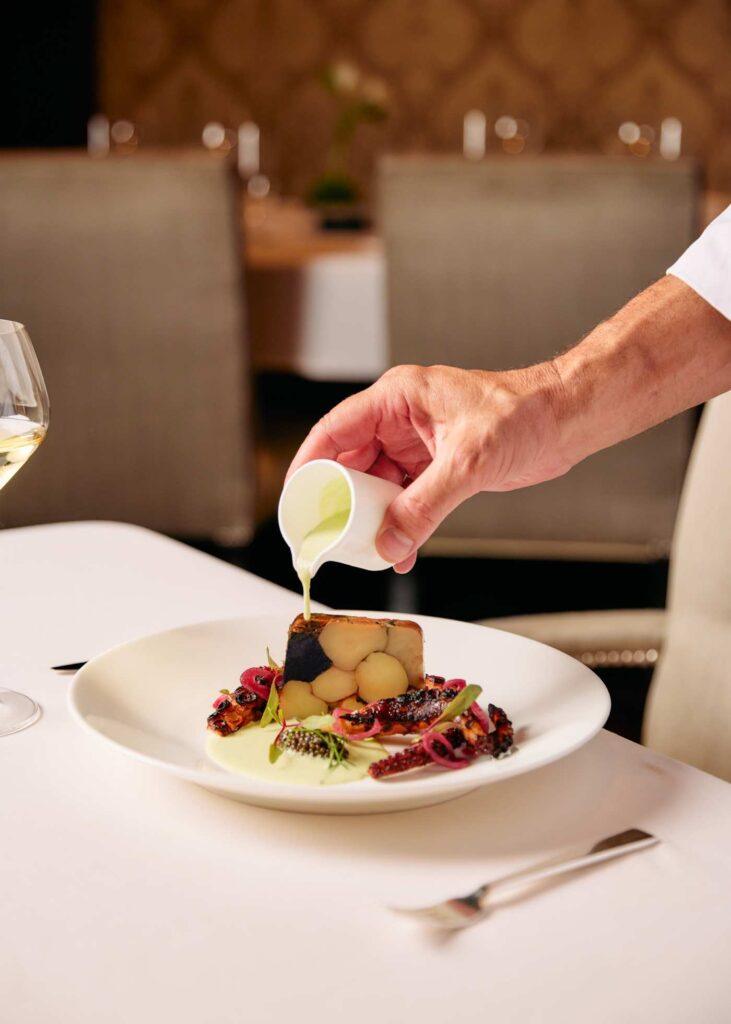 chef pouring the finishing touch over a dish