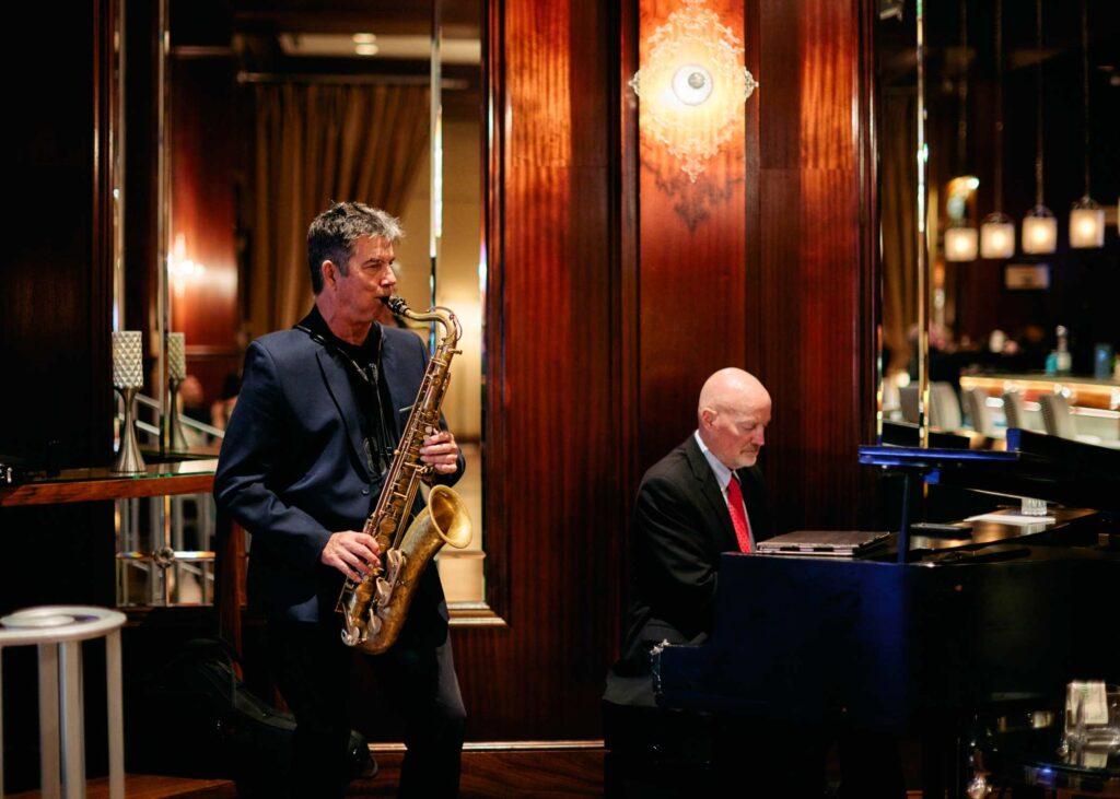 man playing a piano accompanied by a man playing a saxophone