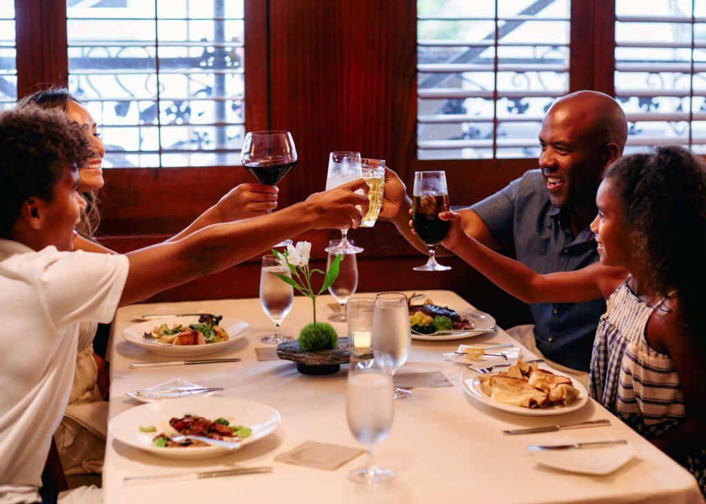 four people clinking glasses over their food