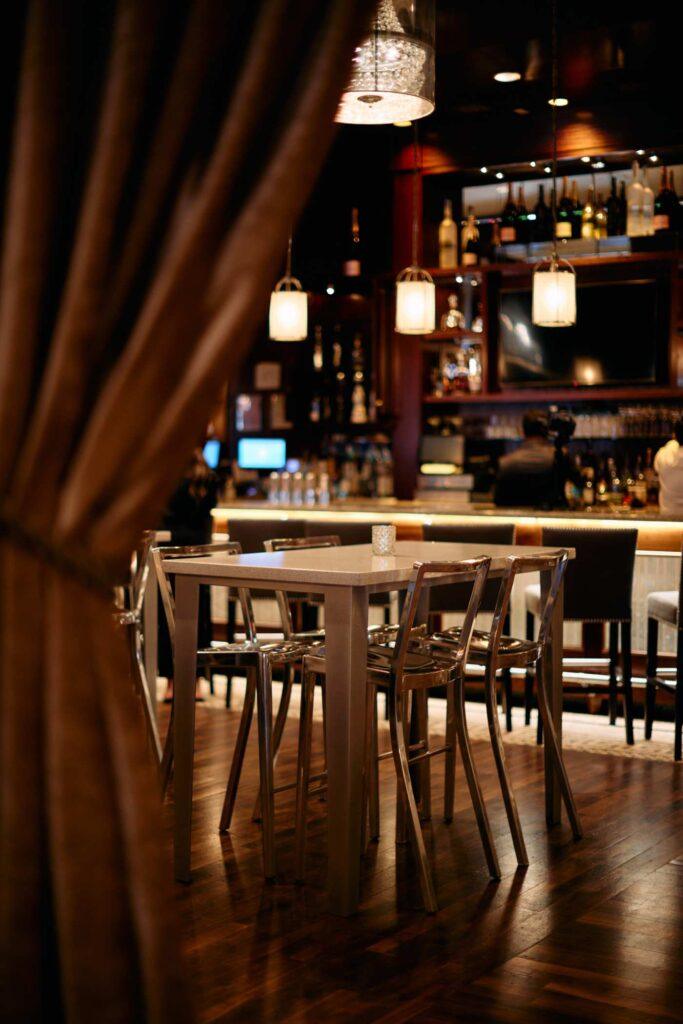 bar table with stools in foreground with bar counter in background