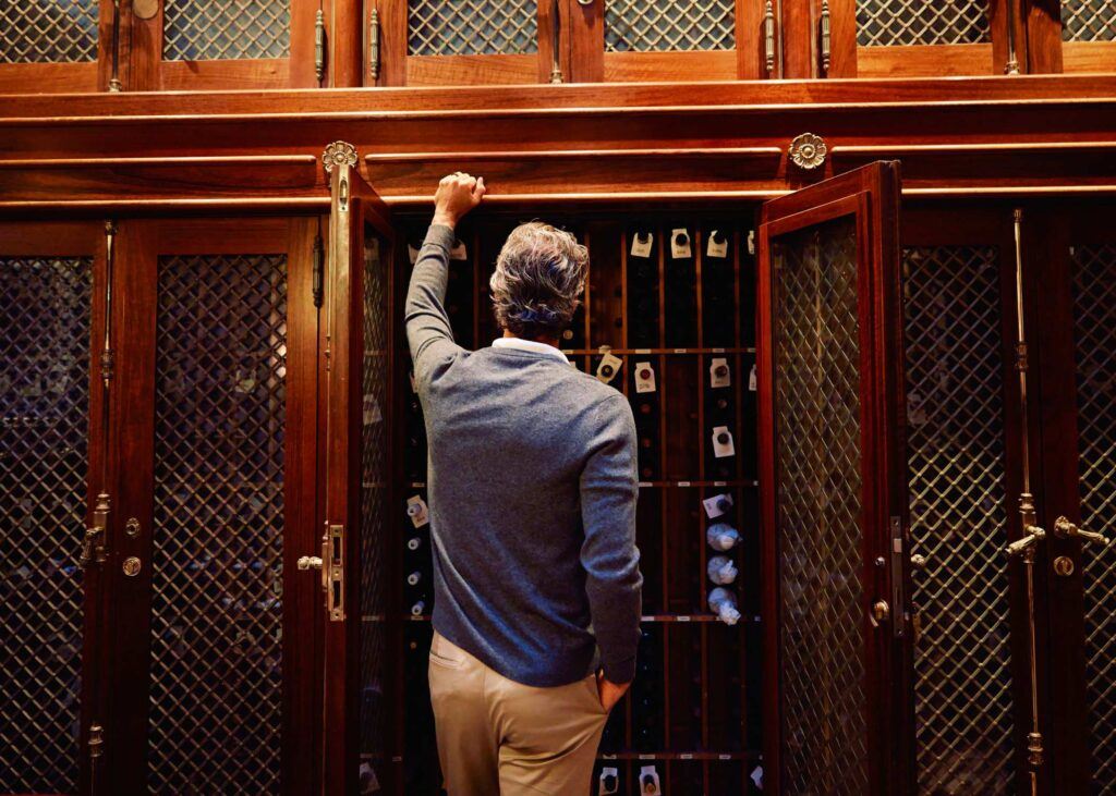 a man leaning against a wine cabinet