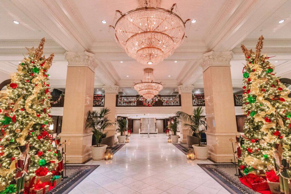 a lobby decorated for christmas with a chandelier hanging from the ceiling